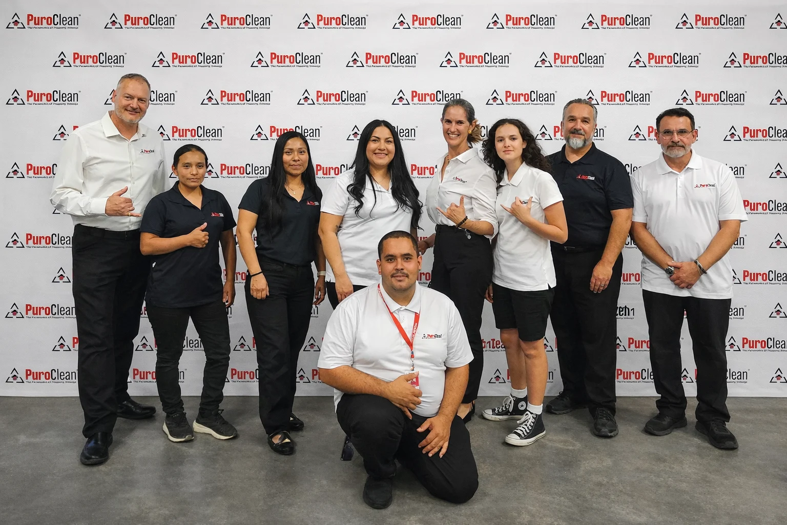 Nine PuroClean staff posed in front of branded step-and-repeat banner, PuroClean of East Las Vegas